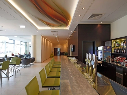 Blick der Bar entlang in einen Gang. Links mehrere Sitzmöglichkeiten. Rechts der Arbeitsbereich hinter der Bar.